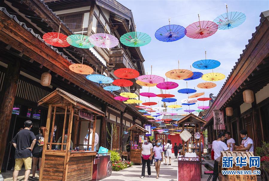 6月13日，市民在長(zhǎng)春市世茂蓮花山小鎮(zhèn)寬厚里商街參觀游覽。 當(dāng)日是“文化和自然遺產(chǎn)日”。吉林長(zhǎng)春首屆蓮花山消夏生活節(jié)在世茂蓮花山小鎮(zhèn)舉行?；顒?dòng)將非遺展示與假日消暑休閑相結(jié)合，讓游人在“古色古香”的油紙傘巷中品傳統(tǒng)文化魅力，享夏日休閑愜意。 新華社記者 許暢 攝