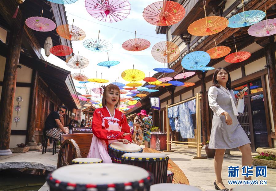 6月13日，在長(zhǎng)春市世茂蓮花山小鎮(zhèn)寬厚里商街，一名古裝愛好者演奏手鼓。 當(dāng)日是“文化和自然遺產(chǎn)日”。吉林長(zhǎng)春首屆蓮花山消夏生活節(jié)在世茂蓮花山小鎮(zhèn)舉行。活動(dòng)將非遺展示與假日消暑休閑相結(jié)合，讓游人在“古色古香”的油紙傘巷中品傳統(tǒng)文化魅力，享夏日休閑愜意。 新華社記者 許暢 攝