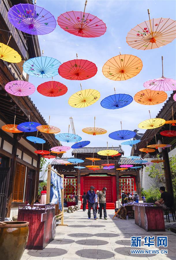 6月13日，市民在長(zhǎng)春市世茂蓮花山小鎮(zhèn)寬厚里商街參觀游覽。 當(dāng)日是“文化和自然遺產(chǎn)日”。吉林長(zhǎng)春首屆蓮花山消夏生活節(jié)在世茂蓮花山小鎮(zhèn)舉行?；顒?dòng)將非遺展示與假日消暑休閑相結(jié)合，讓游人在“古色古香”的油紙傘巷中品傳統(tǒng)文化魅力，享夏日休閑愜意。 新華社記者 許暢 攝