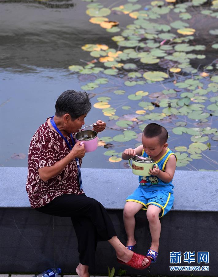 7月14日，在宿松縣洲頭鄉(xiāng)中心小學(xué)集中安置點(diǎn)，洲頭鄉(xiāng)泗洲村的村民在吃晚餐。 近日，安徽省宿松縣洲頭鄉(xiāng)泗洲村的300多名村民因洪水被轉(zhuǎn)移到該鄉(xiāng)中心小學(xué)集中安置點(diǎn)。安置點(diǎn)工作人員、志愿者利用學(xué)校食堂為村民們烹飪飯菜，讓村民們?cè)诎仓命c(diǎn)吃上熱騰騰的三餐。 新華社記者 劉軍喜 攝