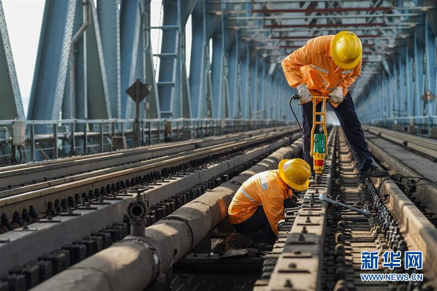 8月6日，兩名橋隧工在南京長江大橋作業(yè)點擰緊螺帽，固定護(hù)木。新華社記者 李博 攝