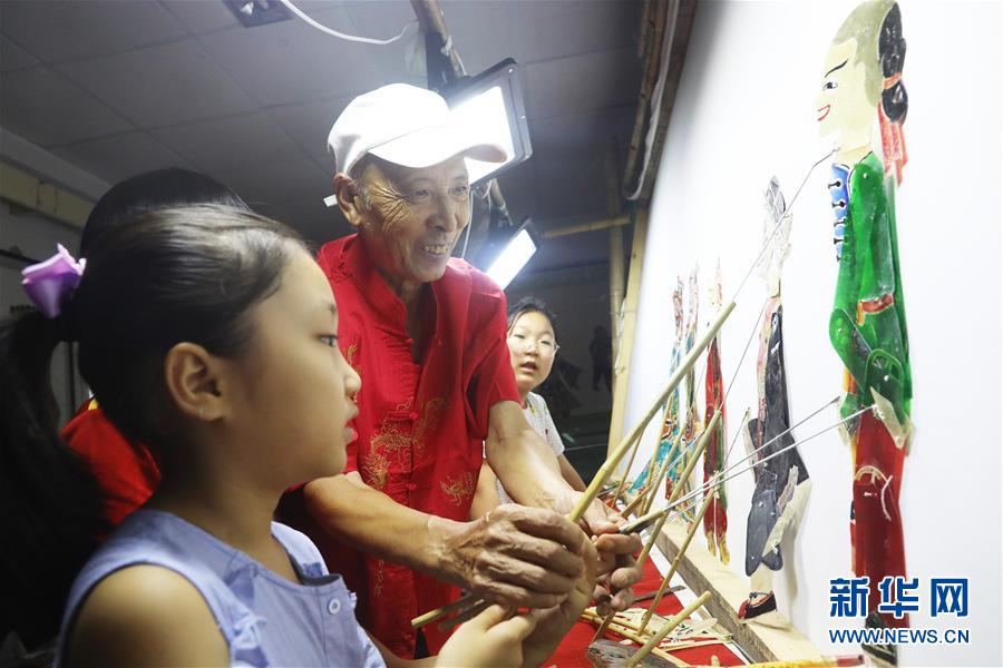 8月14日，皮影戲藝人在河北省唐山市豐潤區(qū)文化館指導小朋友表演皮影戲。 暑假期間，各地的孩子們通過豐富多彩的活動樂享假期、充實生活。 新華社發(fā)（朱大勇 攝）