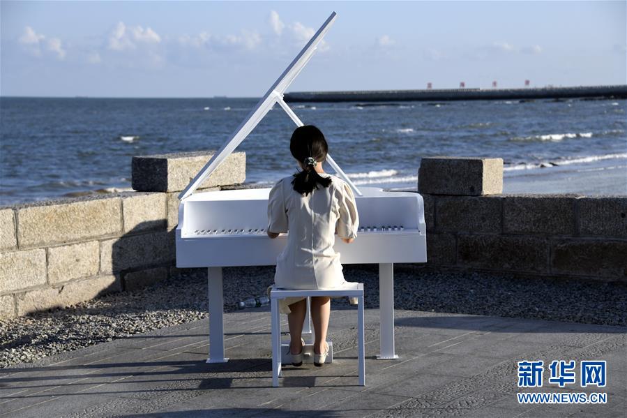 9月26日，一名游客在日照市海洋美學(xué)館面朝大海彈奏鋼琴。 當(dāng)日，山東日照市天氣晴好，陽光明媚，不少市民和游客來到海邊游玩。 新華社記者 范長國 攝
