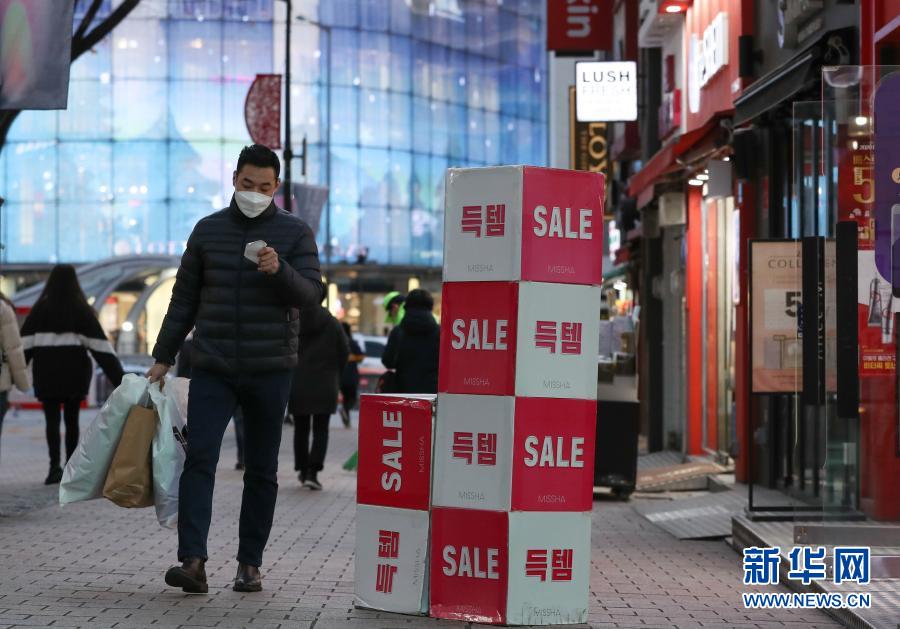 12月8日，在韓國(guó)首爾明洞，一名戴口罩的男子經(jīng)過一家打折店鋪。新冠疫情近期在韓國(guó)再次出現(xiàn)反彈且持續(xù)擴(kuò)散，韓國(guó)政府從8日零時(shí)起再次上調(diào)全國(guó)保持社交距離防疫級(jí)別，進(jìn)一步收緊防疫措施。從8日起，首爾、仁川、京畿道等首都圈地區(qū)的防疫級(jí)別從2級(jí)提升至2.5級(jí)，其他非首都圈地區(qū)從1.5級(jí)提升至2級(jí)，暫定實(shí)施3周。新華社記者 王婧嬙 攝