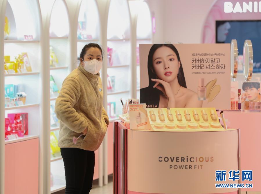 12月8日，在韓國(guó)首爾明洞一家化妝品店，戴口罩的店員望向門外。新冠疫情近期在韓國(guó)再次出現(xiàn)反彈且持續(xù)擴(kuò)散，韓國(guó)政府從8日零時(shí)起再次上調(diào)全國(guó)保持社交距離防疫級(jí)別，進(jìn)一步收緊防疫措施。從8日起，首爾、仁川、京畿道等首都圈地區(qū)的防疫級(jí)別從2級(jí)提升至2.5級(jí)，其他非首都圈地區(qū)從1.5級(jí)提升至2級(jí)，暫定實(shí)施3周。新華社記者 王婧嬙 攝