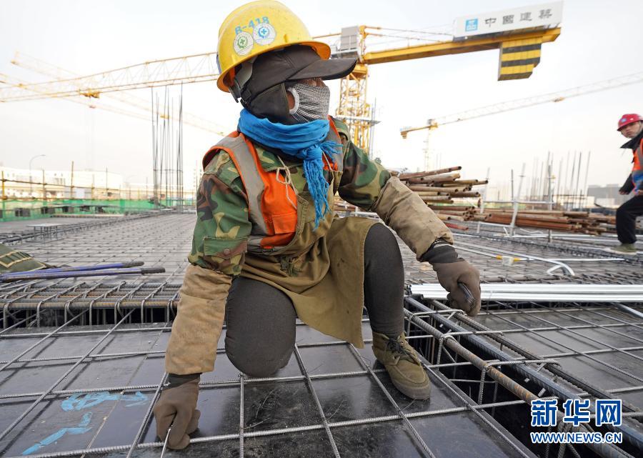 12月17日，在中建三局北京大興國際機(jī)場東航基地項(xiàng)目工地，工人在綁扎鋼筋。近日，伴著寒潮到來，多地迎來寒冷天氣。在北京大興國際機(jī)場東航基地項(xiàng)目工地，勞動者們在凜冽寒風(fēng)中堅(jiān)守崗位。新華社記者 才揚(yáng) 攝