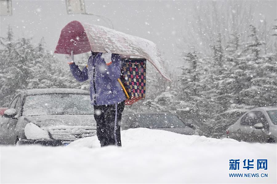 1月5日，在山東煙臺街頭，行人冒雪出行。 當日是小寒節(jié)氣，受強冷空氣影響，山東煙臺迎來降雪。 新華社發(fā)（唐克 攝）