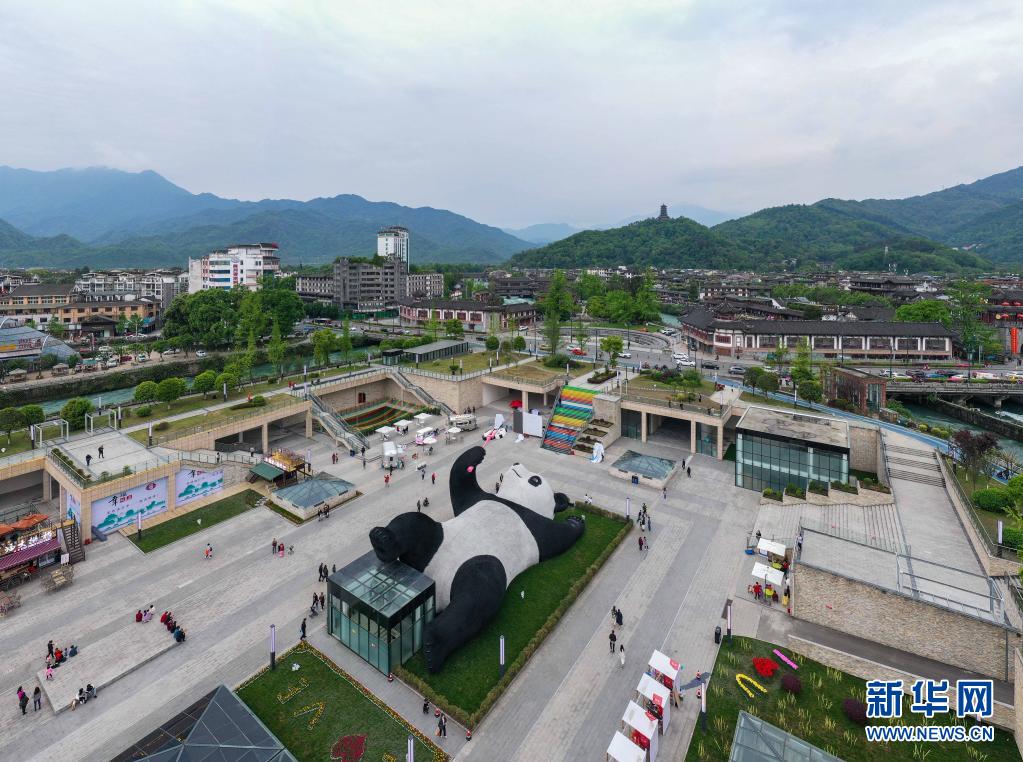 　　這是4月7日在四川省都江堰市仰天窩廣場(chǎng)拍攝的“自拍熊貓”雕塑（無(wú)人機(jī)照片）。　　近日，由荷蘭藝術(shù)家弗洛倫泰因·霍夫曼設(shè)計(jì)的大熊貓自拍藝術(shù)品雕塑在四川省都江堰市仰天窩廣場(chǎng)與公眾見(jiàn)面。這只仰臥翹腳自拍的“大熊貓”長(zhǎng)26.5米、寬11米、高12米，重達(dá)130噸，由300萬(wàn)根漆面不銹鋼絲固定而成?！　?jù)了解，這只熊貓雕塑以2005年大熊貓闖入都江堰鬧市區(qū)的故事為創(chuàng)作靈感。熊貓手持一部巨型智能手機(jī)，吸引市民和游客前來(lái)觀賞，合影“打卡”?！　⌒氯A社記者 王曦 攝