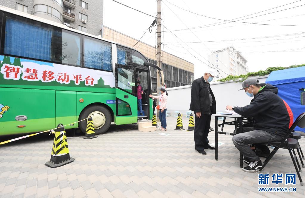 　　4月11日，在北京市海淀區(qū)羊坊店街道小馬廠社區(qū)新冠疫苗臨時接種點(diǎn)，街道工作人員（右一）為接種完新冠疫苗的接種人員填寫留觀卡?！　〗?，北京市海淀區(qū)首輛移動疫苗接種車在羊坊店街道投入使用。據(jù)了解，該移動疫苗接種車內(nèi)劃分有1個登記臺和2個接種臺，車上配備醫(yī)用冷藏箱、空調(diào)等設(shè)備，保障新冠疫苗順利接種?！　⌒氯A社記者 任超 攝